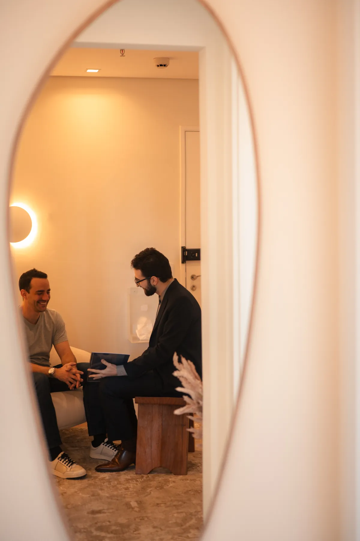 Médico e paciente conversando durante a consulta, refletidos no espelho da recepção